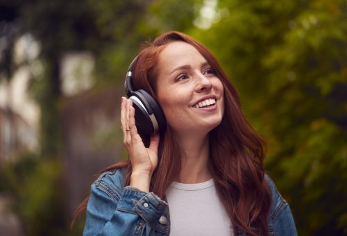 Female Vlogger Or Social Influencer Wearing Headphones Travelling Through City